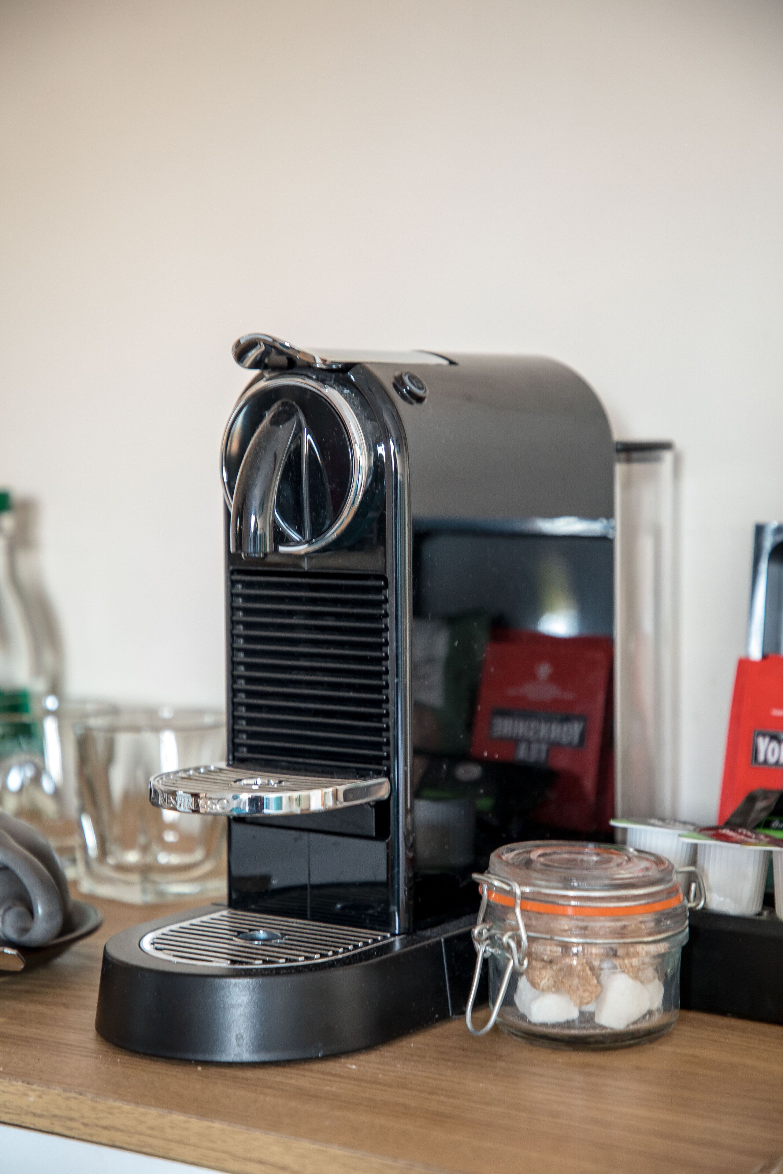 Una cafetera sobre una superficie de madera con un tarro de vidrio que contiene granos de café.