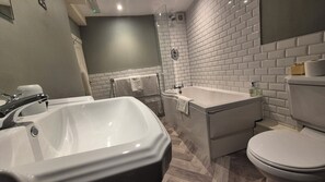 A modern bathroom with a large bathtub, a separate shower area, and a toilet.