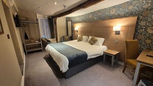 A bedroom with a large bed, bedside tables, a chair, and a mirror. - The Snooty Fox (Carnforth)