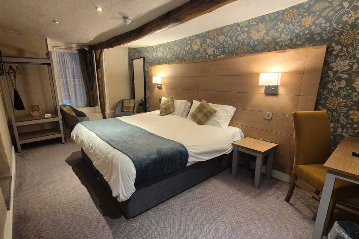 Ein Schlafzimmer mit einem großen Bett, Nachttischen, einem Sessel und einem Spiegel.