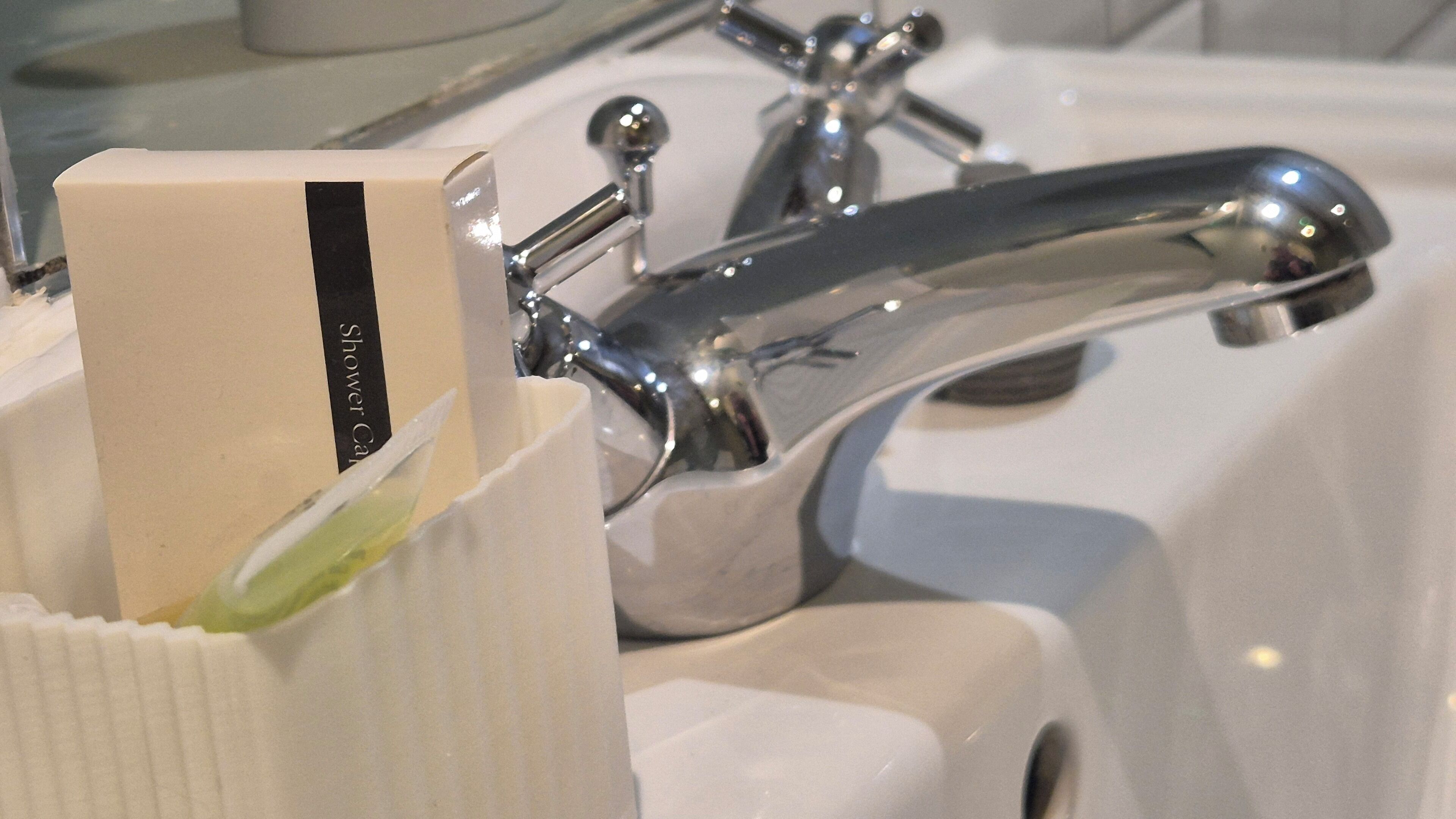 A bathroom sink with a chrome faucet and a soap dispenser in a holder.