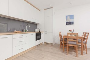 A modern kitchen with white cabinets, a wooden countertop, and a dining area with a wooden table and chairs.