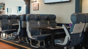 A row of reclining seats with tables in a hotel lobby. - The Oak (Coventry)