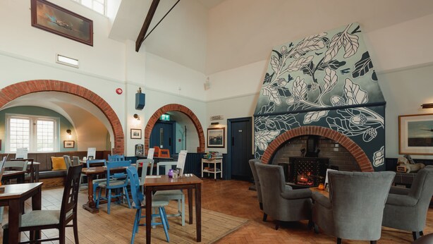 A spacious lobby with a fireplace, seating areas, and a view of the outside. - The Oak (Coventry)