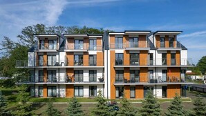 A modern multi-story residential building with balconies, large windows, and a well-maintained lawn. - Modern Apartment | 550 m to the Beach | Parking | Spa (Międzywodzie)