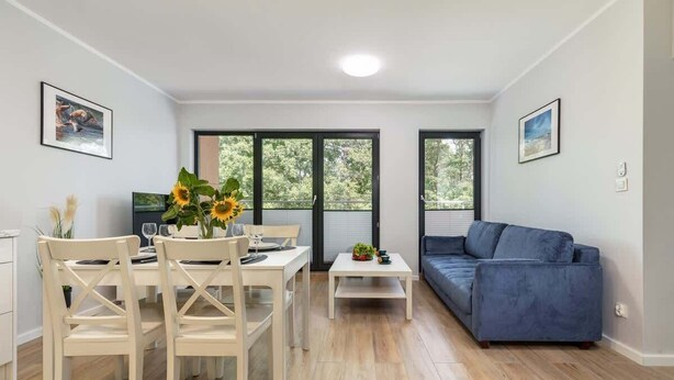 A modern living room with a dining area, a sofa, and large windows. - Modern Apartment | 550 m to the Beach | Parking | Spa (Międzywodzie)