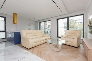 En moderne stue med to beige sofaer, et glasbord og et blå skab.
