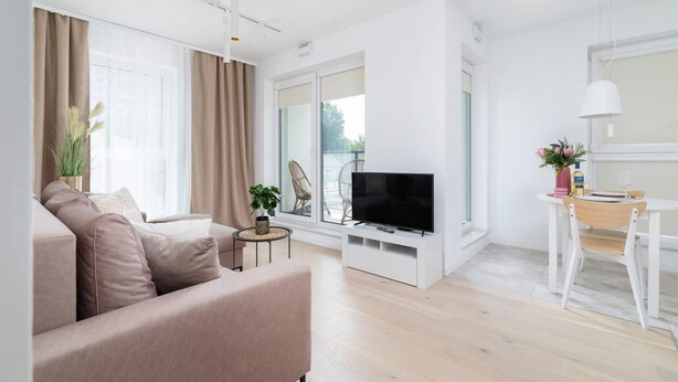 Ein modernes Wohnzimmer mit Sofa, Fernseher und Essbereich.