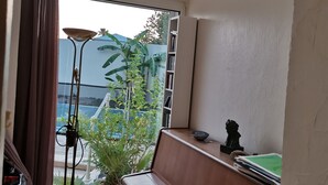 A room with a bench, a bookshelf, a small table, and a window with curtains. - Spacious villa close to center and beaches. (Hyères)
