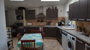 A compact kitchen with a dining area, equipped with a microwave, oven, and washing machine. - Spacious villa close to center and beaches. (Hyères)