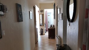 A hallway with a tiled floor, a black console table, a mirror, and a ceiling light fixture. - Spacious villa close to center and beaches. (Hyères)