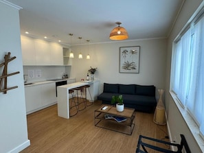Un espacio habitable moderno con cocina, comedor, sofá y mesa de centro.