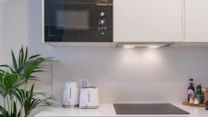 Une cuisine compacte équipée d’un four à micro-ondes, d’un grille-pain et agrémentée d’une plante en pot.