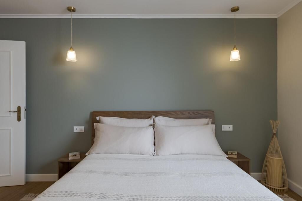 Une chambre à coucher comprenant un lit, deux tables de chevet, une commode et une lampe fixée au mur.