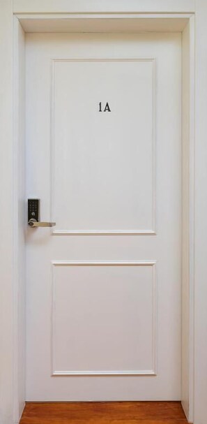 A white door with the number 1A on it, a keypad lock, and a wooden floor. - Peixeira Studios and Apartments (Lisbon)