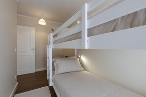 Een slaapkamer met een stapelbed, een witte deur en een lamp boven het bed.