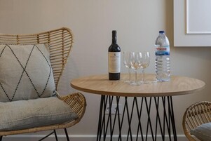 Una mesa de madera redonda con una botella de vino, dos copas y una botella de agua.