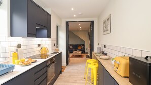 Eine moderne Küche mit dunklen Schränken, einer Holzausziehtafel und einem gelben Toaster.