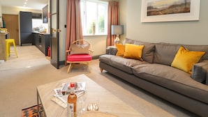 Ein Wohnzimmer mit einer Couch, Sesseln, einem Couchtisch und einem Essbereich mit Tisch und Stühlen.