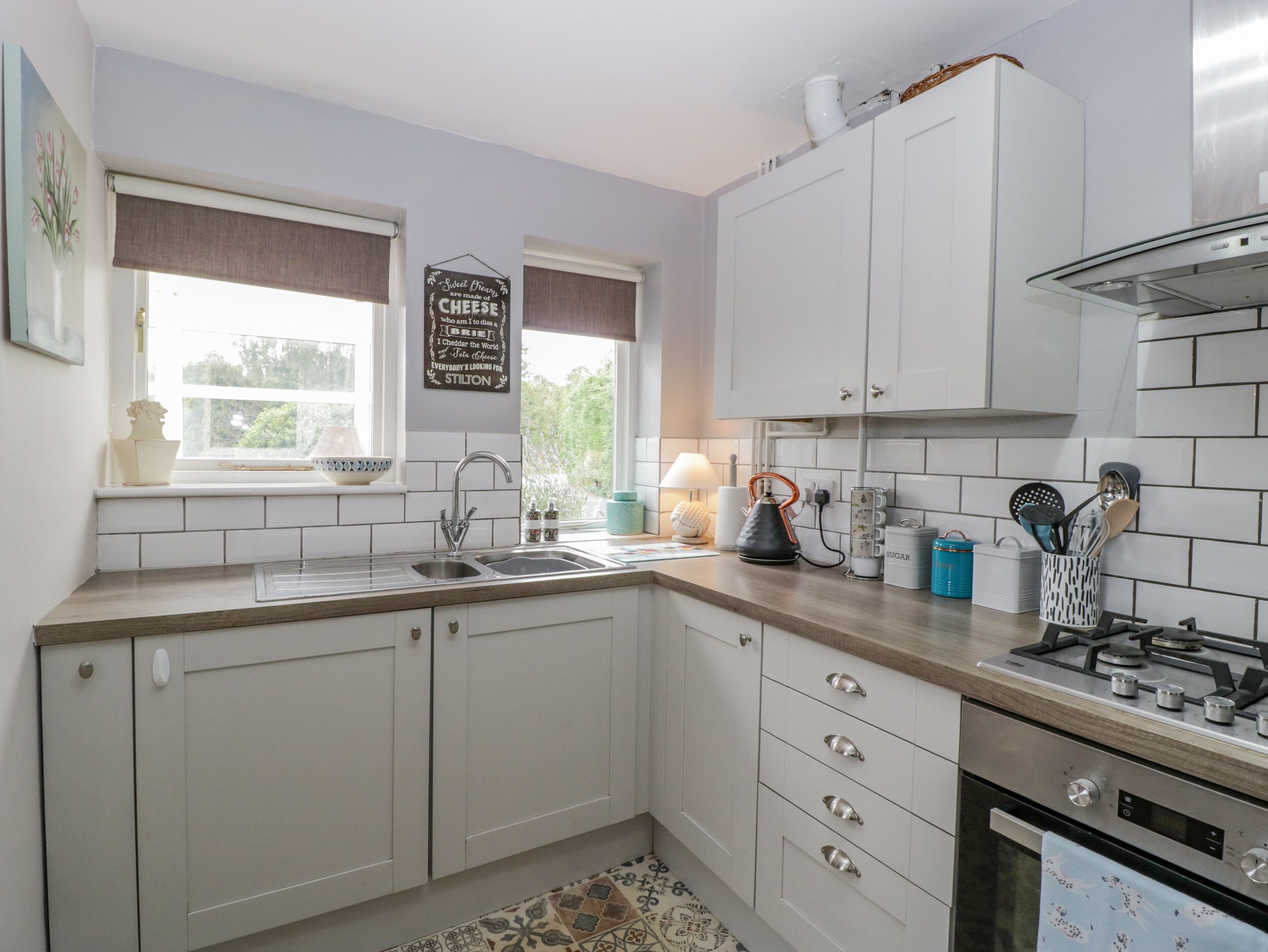 A kitchen with white cabinets, a gas stove, a sink, and a window with a view of greenery.