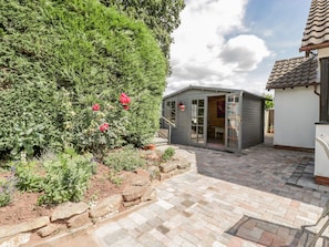 A garden with a shed, stone pathway, and a variety of plants.