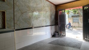 A hallway with marble walls, a tiled floor, and a metal gate leading outside. - Gia Bao Hotel (Ho Chi Minh City)