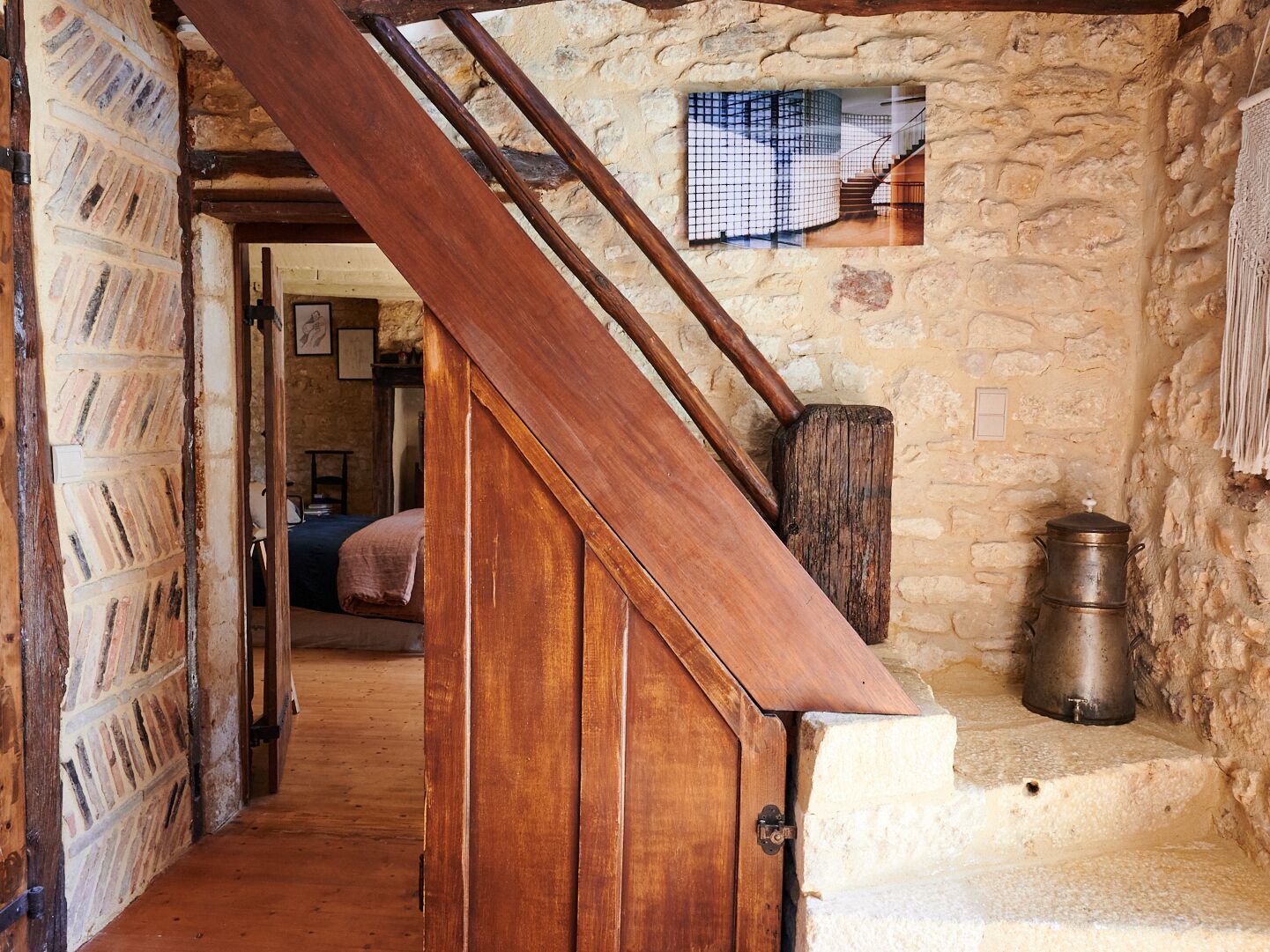 Een rustiek interieur met een houten trap, stenen muren en een klein raam.