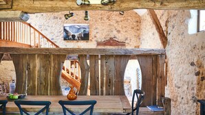 Ein rustikaler Essbereich aus Holz mit einem Holztisch und Stühlen, einer Steinwand und einer Treppe.