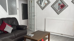 A living room with a brown leather sofa, a wooden coffee table, and a red shag rug.