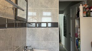A modern bathroom with a white sink, a mirror, and a tiled wall.