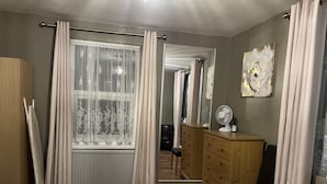 A bedroom with a bed, wooden dresser, and a mirror.