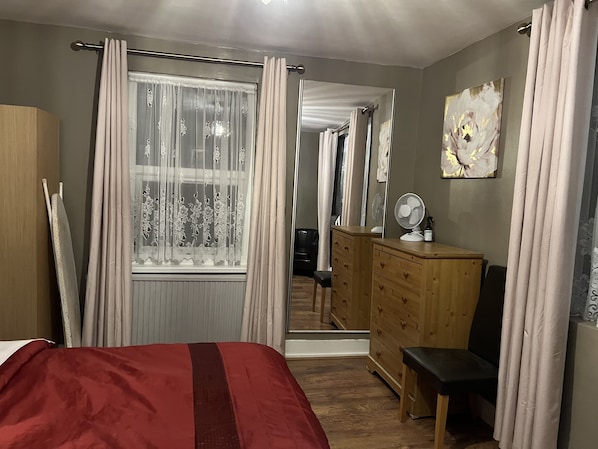 A bedroom with a bed, wooden dresser, and a mirror.