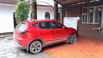 Un coche rojo aparcado frente a un edificio con un cartel que dice '40 PUNTOS DE CARGA y en constante expansión por Nepal'.