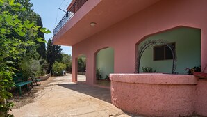 Een gebouw met roze muren, een balkon en een binnentuin met een bank en plantenpotten.