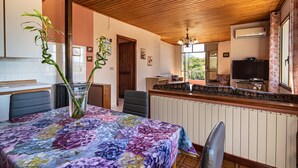 A dining area with a table covered in a floral tablecloth, a chair, a sofa, and a television on a stand. - Holiday Home 'Casa Teresa' with Mountain View, Balcony, and Air Conditioning (Iglesias)