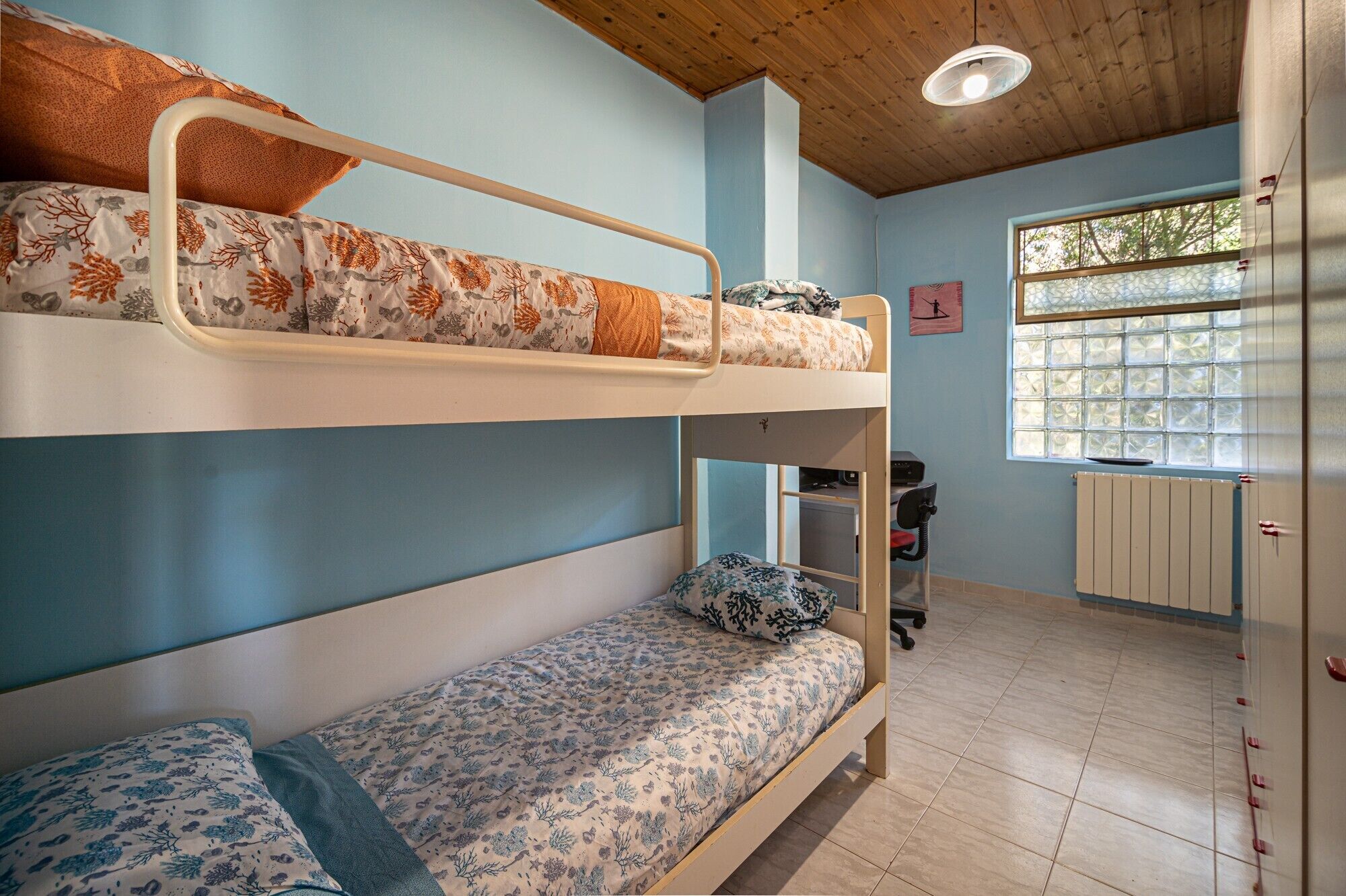 Camera con letto a castello, finestra, termosifone e scrivania.