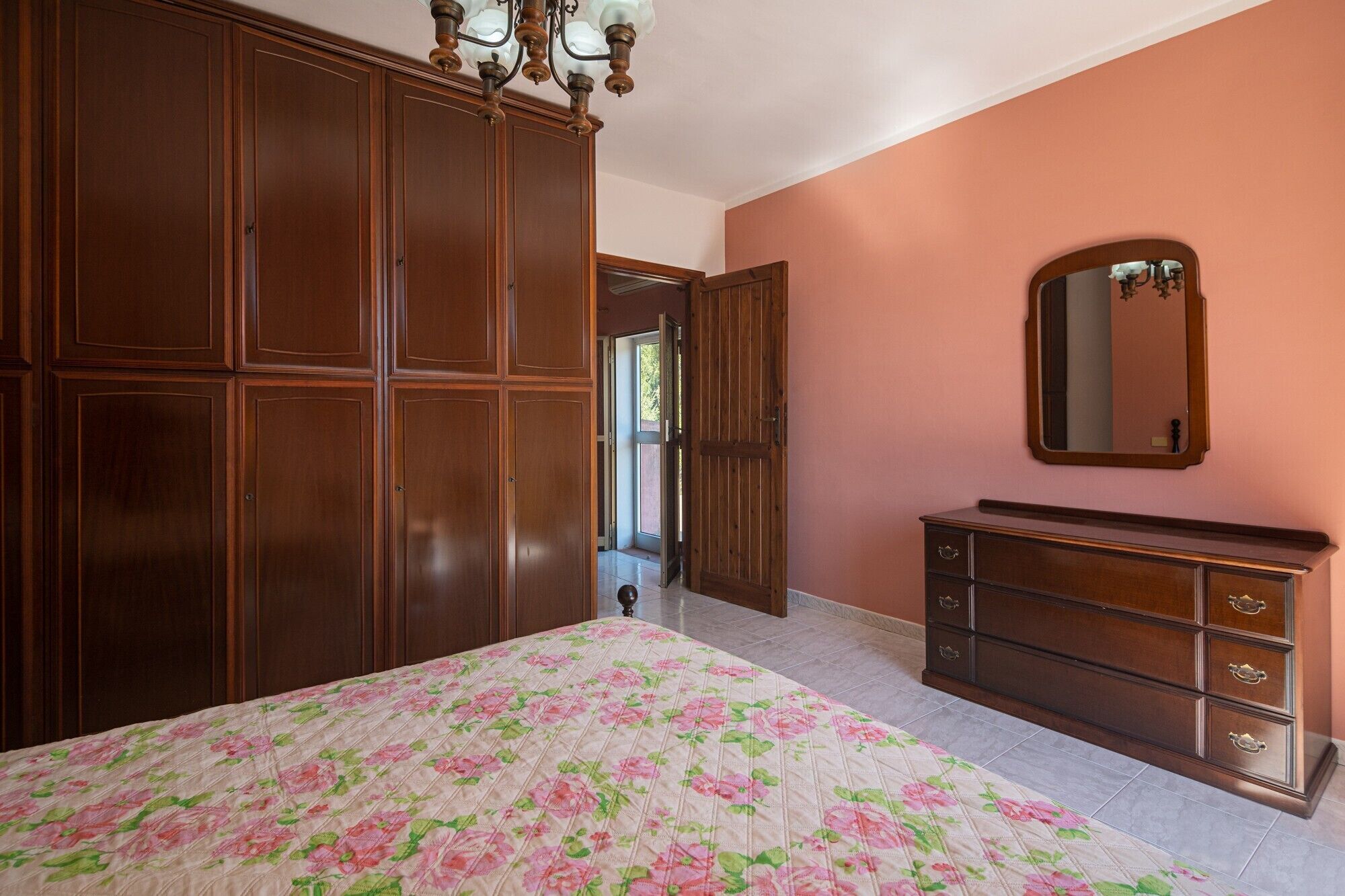 Ein Schlafzimmer mit Bett, Kommode, Spiegel und Kleiderschrank.
