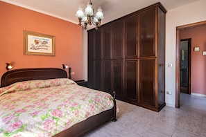 Une chambre à coucher avec un lit, une armoire, un lustre et un tableau encadré au mur.