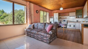 A cozy living area with a sofa, a dining table, and a kitchen with a stove and microwave. - Holiday Home 'Casa Teresa' with Mountain View, Balcony, and Air Conditioning (Iglesias)