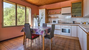 A kitchen with a dining table, chairs, a refrigerator, a microwave, an oven, and a sink. - Holiday Home 'Casa Teresa' with Mountain View, Balcony, and Air Conditioning (Iglesias)