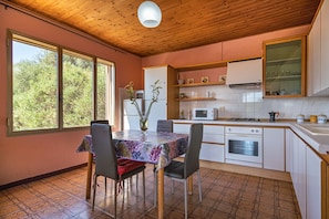 Une cuisine équipée d’une table à manger, de chaises, d’un réfrigérateur, d’un four à micro-ondes, d’un four et d’un évier.