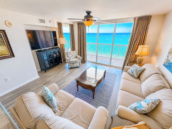 A living room with a sofa set, a coffee table, a television, and a balcony with a view of the ocean. - Crescent Shores S 1209 - Oceanfront Luxury & Unmatched Views! (North Myrtle Beach)