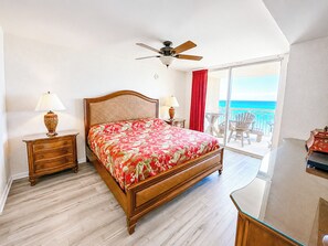 A bedroom with a bed, two bedside tables with lamps, a ceiling fan, and a balcony with a view of the ocean. - Crescent Shores S 1209 - Oceanfront Luxury & Unmatched Views! (North Myrtle Beach)