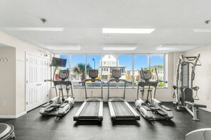Ein Fitnessstudio mit Laufbändern, Krafttrainingsgeräten und einem großen Fenster mit Blick auf Gebäude.