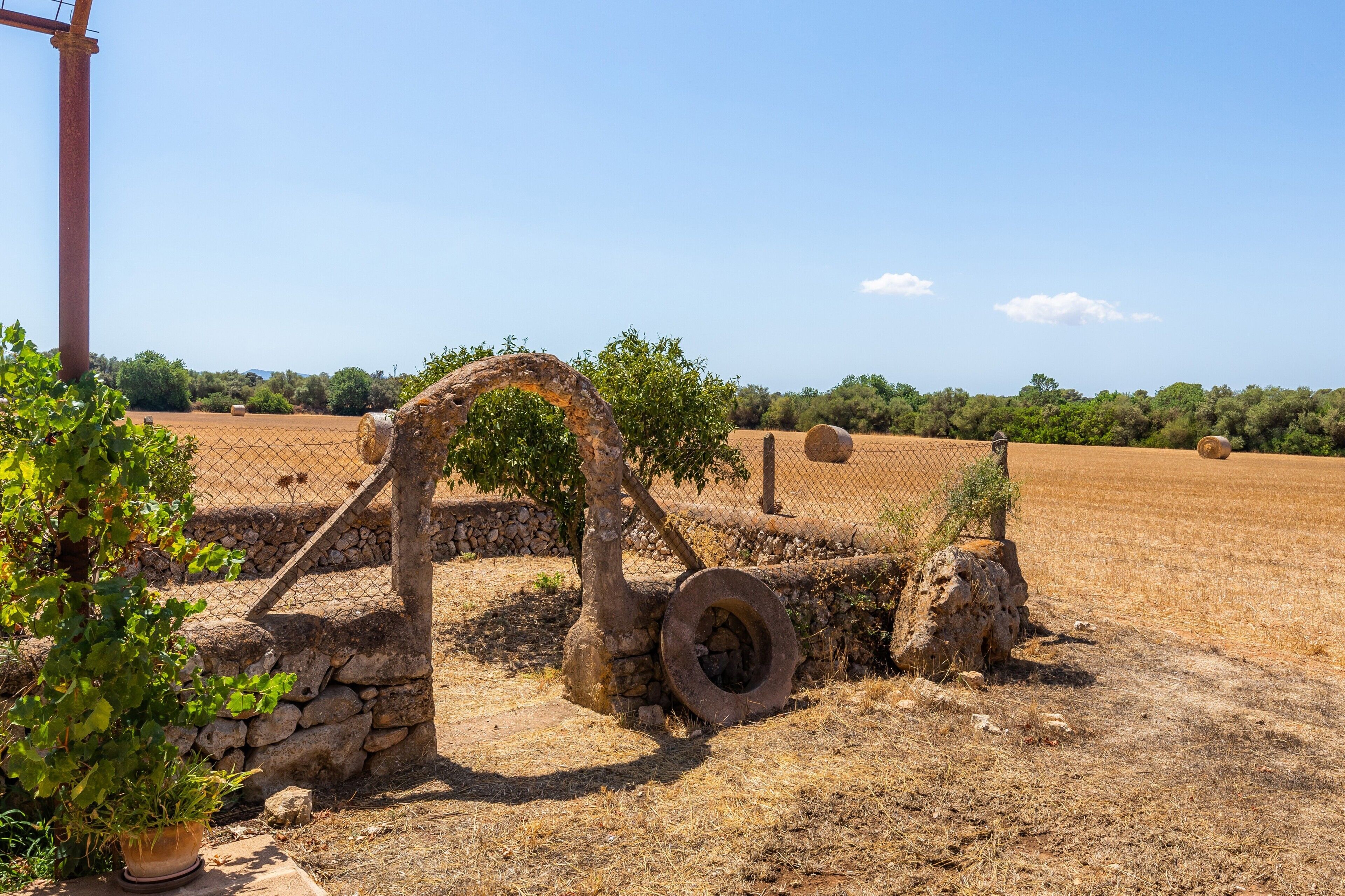 An outdoor area with stone structures, a fence, and a field in the background.