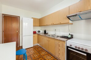 Une cuisine de taille réduite, avec des meubles en bois, un réfrigérateur blanc, une cuisinière et un évier.