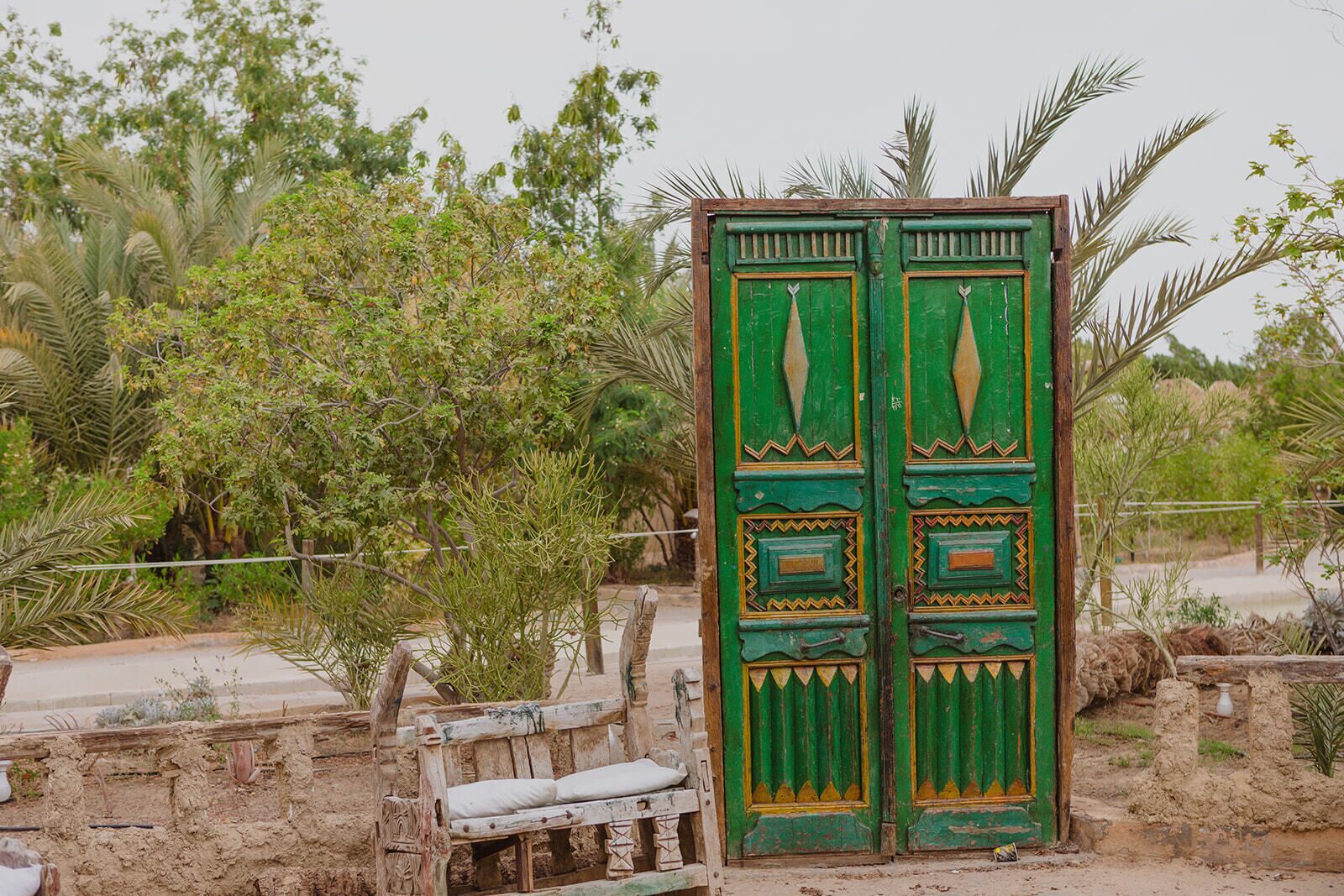 A rustic wooden bench and a green door with decorative patterns.