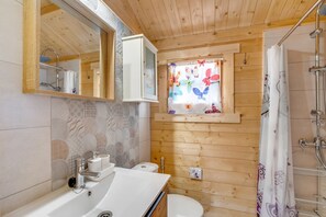 Une salle de bain rustique, aménagée dans une cabane en bois, avec un lavabo, des toilettes et une douche.