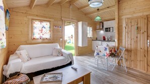 A wooden interior with a sofa, a dining table, and a kitchen area. - Vacation Home 'Finca Mariposa' with Sea View, Garden & Wi-Fi (Adeje)