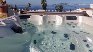 A hot tub with clear water, surrounded by a balcony with plants and a view of the sea. - Vacation Home 'Finca Mariposa' with Sea View, Garden & Wi-Fi (Adeje)
